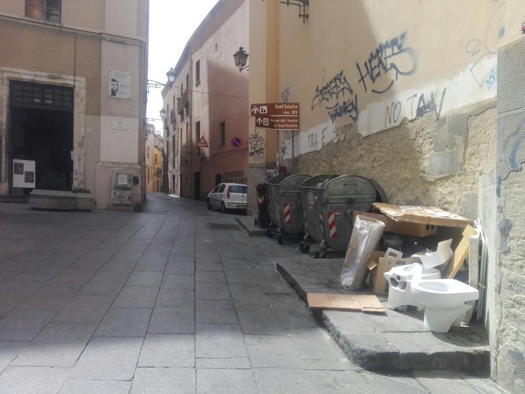 Cagliari, piazzetta Dettori in un sabato mattina d’estate: metti un water accanto ai cassonetti