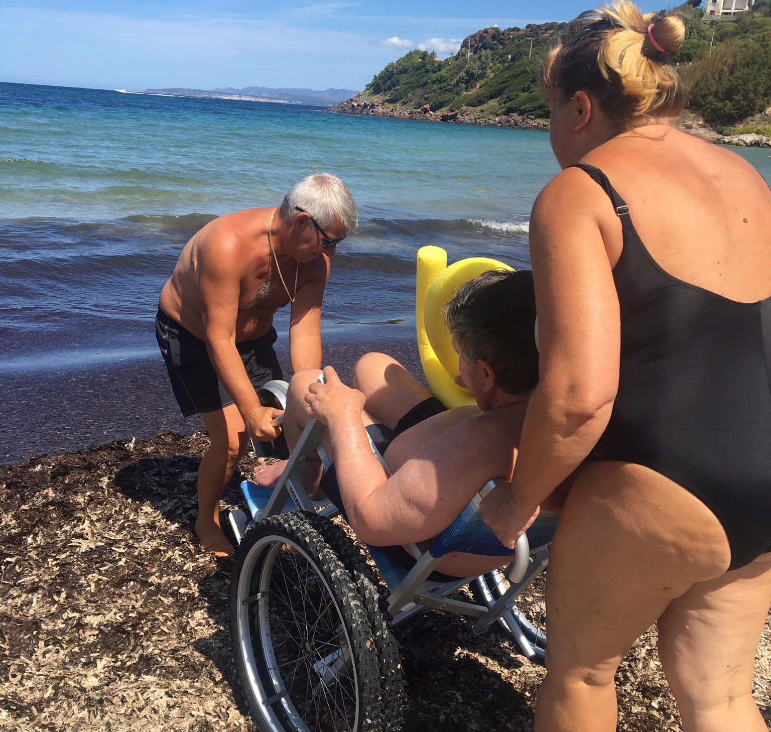 A Calasetta giungla di alghe in spiaggia e nessuno spazio per i disabili: coppia costretta a trascinare la carrozzina