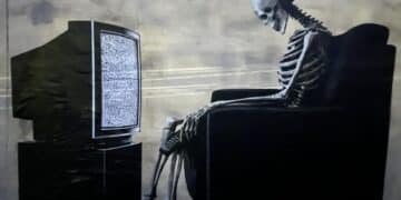 Cagliari, tanta curiosità per lo strano murale a Bonaria: lo scheletro davanti alla tv